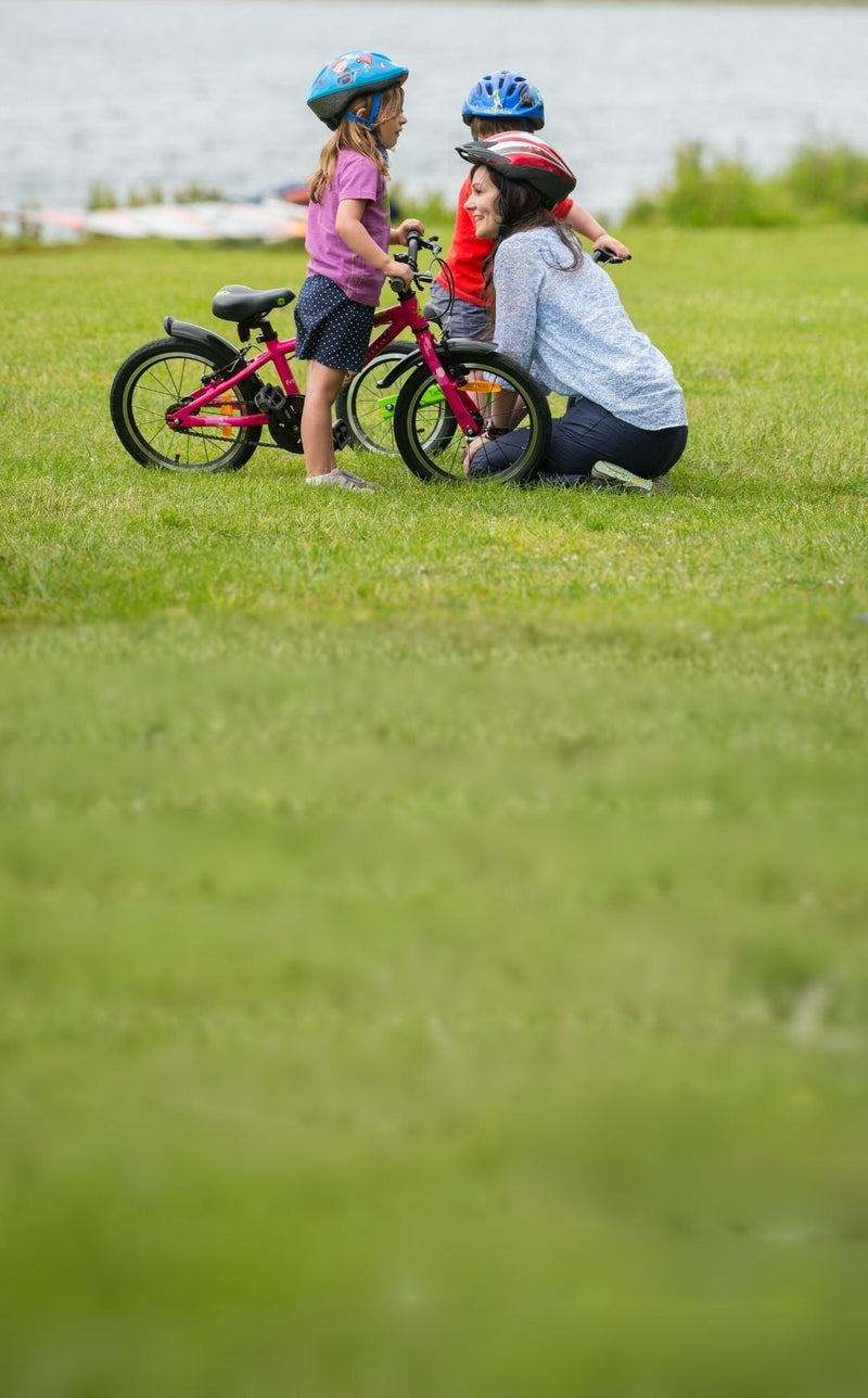Une maman et ses deux enfants à vélo au bord du lac